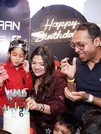A joyful cake-cutting moment at a Ninjago-themed 6th birthday party, complete with a custom cake and a celebratory crown for the birthday boy.
