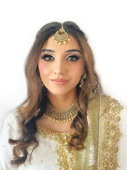 A classic and regal look for a pre-wedding event. The makeup is centered around a defined smokey eye and glowing skin, perfectly paired with traditional gold jewelry and a white and gold outfit.