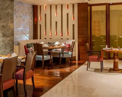 A cozy dining nook at Tamari, featuring custom wall lighting and a mix of upholstered chairs. The space is designed to feel both modern and traditional, with layers of texture and warm tones.