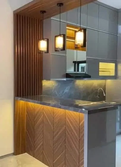 This design features a kitchen peninsula with a breakfast bar. The combination of wood textures, grey gloss cabinets, and pendant lighting creates a sophisticated, modern look.
