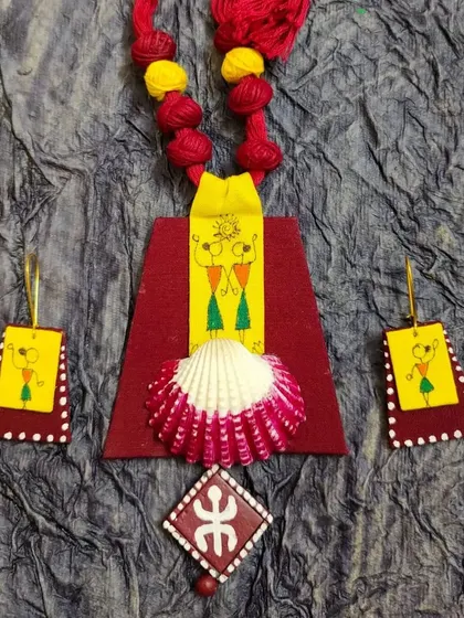 A unique fabric necklace combining Warli art with a painted seashell. This fusion of materials and art forms creates a truly one-of-a-kind piece.