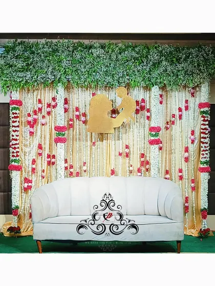 A beautiful Seemantham backdrop with hanging jasmine and rose garlands. The golden mother-child silhouette at the center is a perfect focal point for photos.