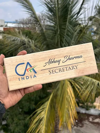 A wooden desk nameplate designed for a Chartered Accountant, featuring the CA India logo and their name and designation.