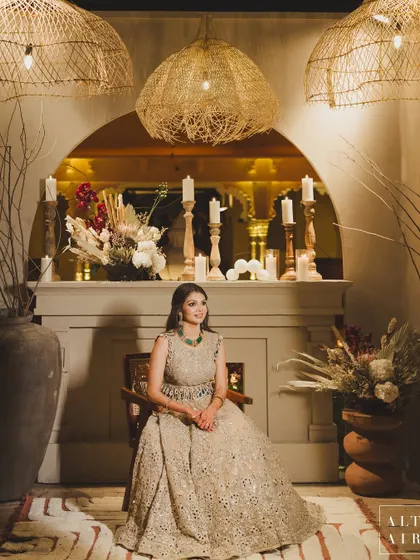The bride looking radiant at her 'Muted Melodies' sangeet. The decor was all about understated luxury, with a cozy fireplace, rattan pendants, and earthy tones creating a moonlit and ethereal evening.