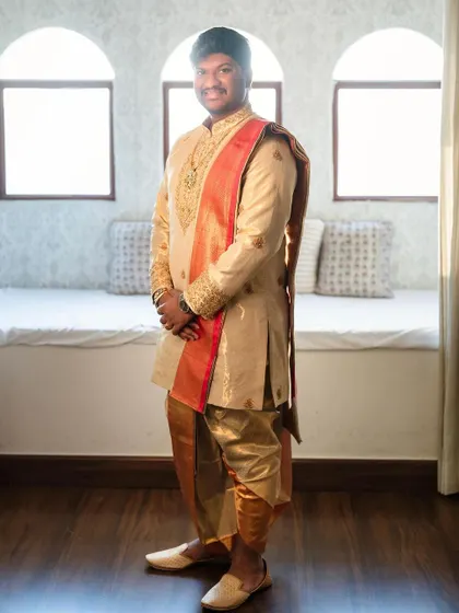 Another view of this stunning groom's outfit. The intricate embroidery on the kurta and the traditional draping of the panche are simply perfect.