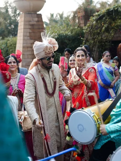 The groom joins in the celebration, dancing with the dhol players and his family. The baraat is the ultimate expression of joy and excitement before the wedding ceremony.