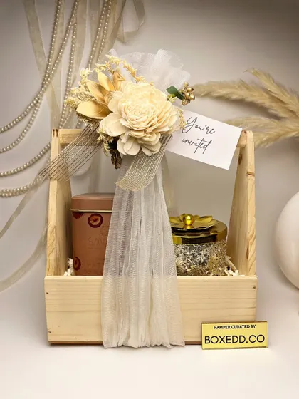 A classy and rustic wedding invitation hamper. This wooden caddy is filled with premium tea and dry fruits, beautifully decorated with sola wood flowers and a simple 'You're Invited' tag.