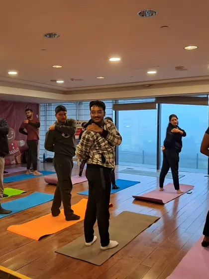 Participants in a corporate yoga class learning some simple shoulder stretches to relieve tension from sitting at a desk.