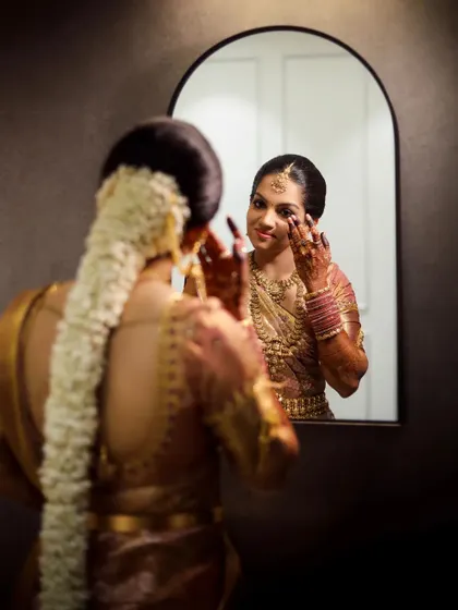 A beautiful shot of the bride looking at her reflection in the mirror, a quiet moment of contemplation before the ceremony begins.