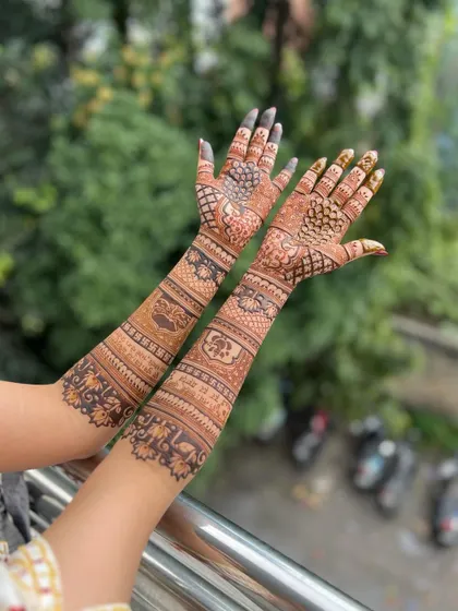 A full-arm design captured outdoors, with the natural background making the henna details stand out.