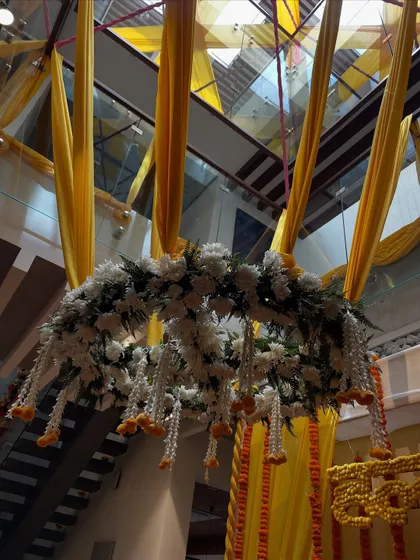 A close-up of a beautiful floral chandelier. This hanging arrangement of white flowers and jasmine strings adds a touch of elegance and fragrance to the venue, perfect for any indoor ceremony.