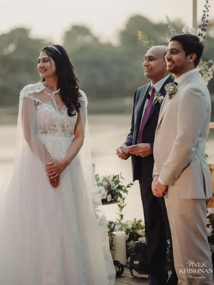 A few moments before they say "I do." The couple stands together at the altar, sharing a look of love and anticipation, with the serene lakeside and elegant floral decor creating a perfect backdrop.