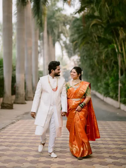 The couple walking hand-in-hand down a path lined with palm trees.