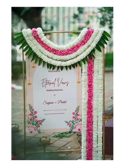 A beautiful welcome sign for the 'Eternal Vows' ceremony, decorated with a traditional floral 'thoran' of white and pink flowers and mango leaves.