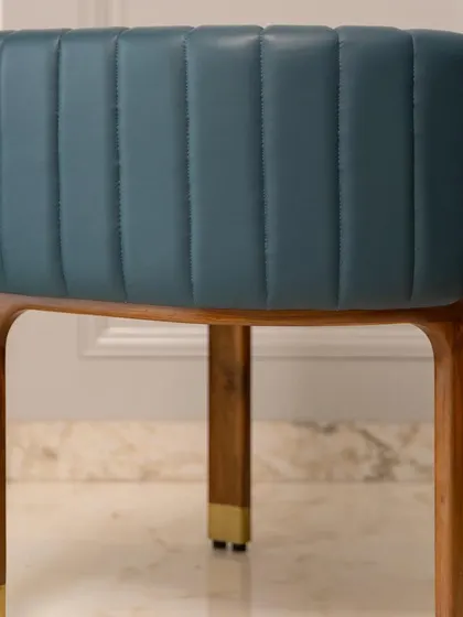 A close-up of the back of our artistic accent chair, revealing the channel-stitched leather and the smooth, curved teakwood frame. Every detail is crafted to tell a story of quality.