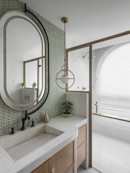 The bathrooms in the Slender House are designed to be spacious and naturally lit. This one features elegant green mosaic tiles, a custom vanity, and a statement pendant light, ensuring optimal function and efficiency.
