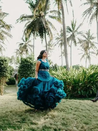 A playful shot in a garden. The client's teal ruffled gown adds a vibrant splash of color and movement to the photo.