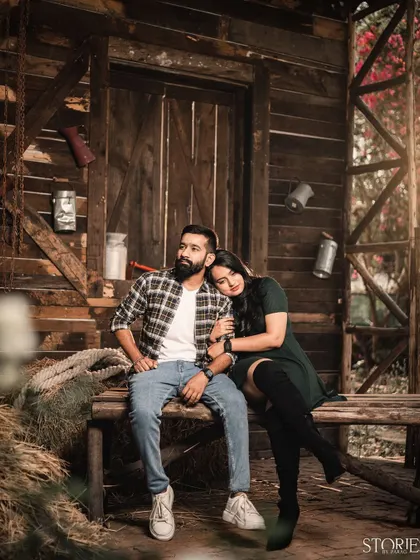 A relaxed portrait in a rustic, barn-like setting. The warm lighting and wooden textures create a cozy and intimate atmosphere for this couple's pre-wedding shoot.