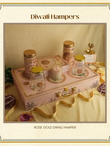 This "Rose Gold" Diwali Hamper combines modern elegance with festive cheer. The pink and gold box contains a curated selection of treats and a decorative candle.