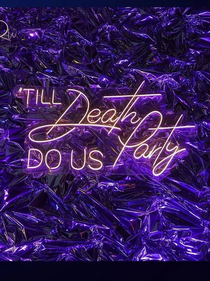 A cheeky neon sign reading "Till Death Do Us Party" against a metallic purple backdrop, perfectly capturing the fun and edgy vibe of the cocktail night.