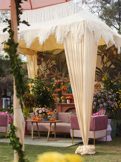 An elegant canopy with fringe detailing provided shade for a lounge area, complete with a beautiful botanical mural backdrop.