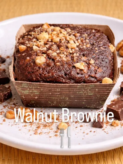 A walnut brownie topped with chopped nuts appears in this display of a sweet we pair with savoury snack-box items.