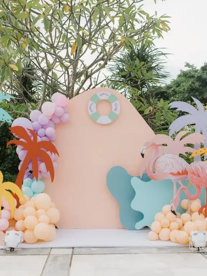 A fun, colorful photo booth setup with flamingo and palm tree cutouts for a tropical pool party in Bali.