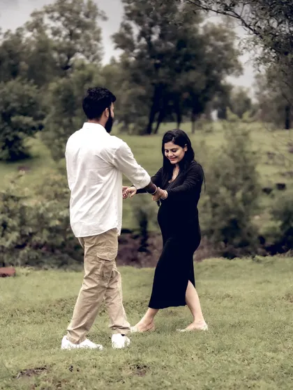 A playful moment of the couple dancing in a field, surrounded by trees. It’s a candid shot that shows their fun-loving relationship.