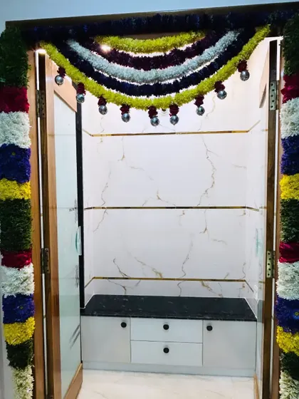 A simple pooja unit door decorated with colorful flower garlands. Even a small touch of fresh flowers can make the space feel more divine.