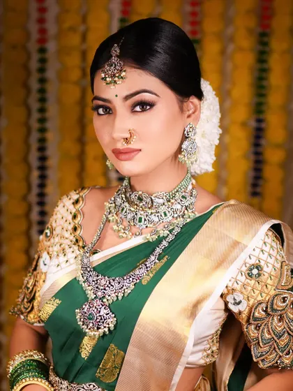 A stunning portrait of a bride ready for her reception. The green and gold saree is paired with intricate silver jewelry, and the makeup is kept bold and defined for a truly regal look.