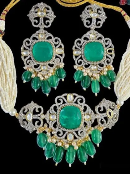 This is a truly royal-looking choker set with large green stones and fine American diamond work. The necklace comes on a string of pearls, giving it a very rich and sophisticated feel, perfect for a bride.