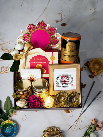 A closer look at the details in our luxury Diwali hamper. This arrangement includes traditional motichoor ladoo, jars of premium nuts, wafer sticks, fragrant incense, and hand-painted diyas, all centered around a personalized photo frame to make your gift truly unique.