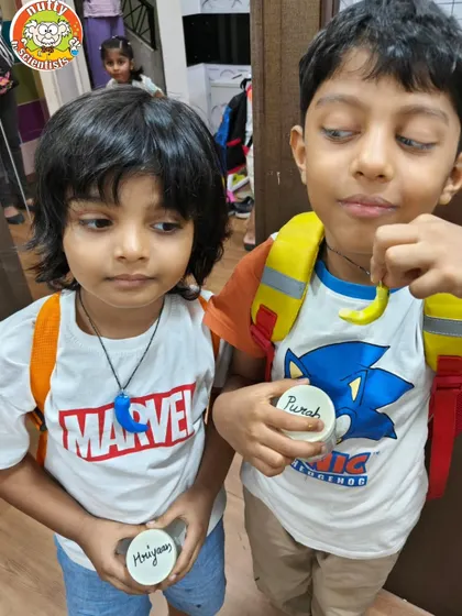 Two friends comparing their custom-painted dino-tooth necklaces. This is a great activity for workshops and birthday parties, allowing for individual creativity.