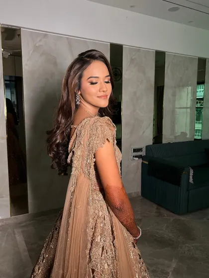 A soft and glossy sangeet glam. I love how the light catches the highlighter on her skin, giving her a beautiful, ethereal glow that complements her golden outfit.