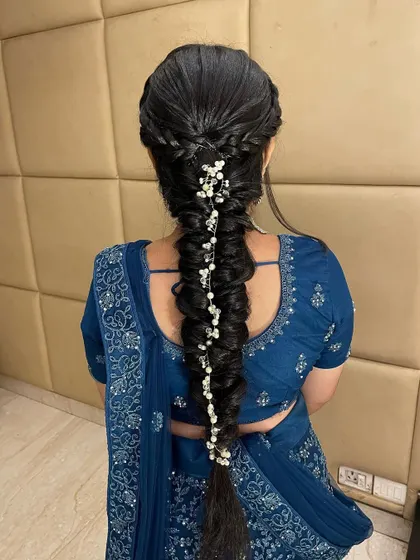 The hairstyle is just as important as the makeup. This intricate fishtail braid adorned with pearls was the perfect complement to her elegant lehenga.