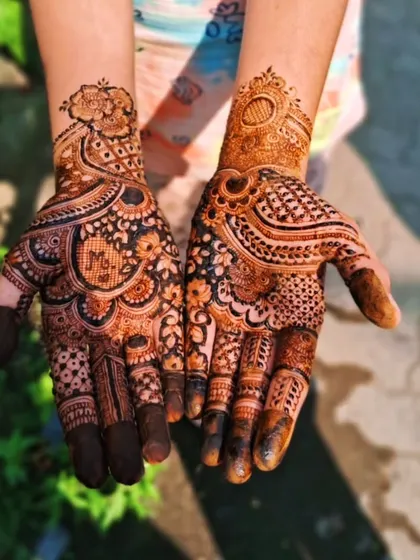 A lovely stained bridal mehendi photographed outdoors. The natural light highlights the rich brown and orange tones of the mature henna stain.