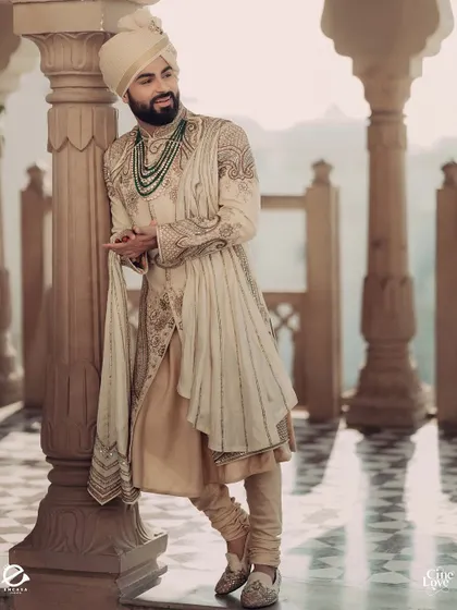 A portrait of the groom, leaning against a pillar of the Mughal-inspired arches. The soft light and serene backdrop create a timeless and elegant image.