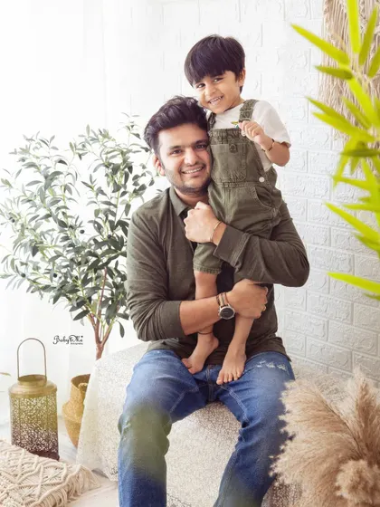 A proud father holding his son. The coordinated green and denim outfits look great in the natural, earthy tones of my boho studio setup.