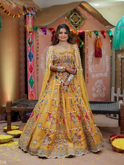 A stunning full-length portrait of the bride in her heavily embroidered yellow lehenga with a cape.