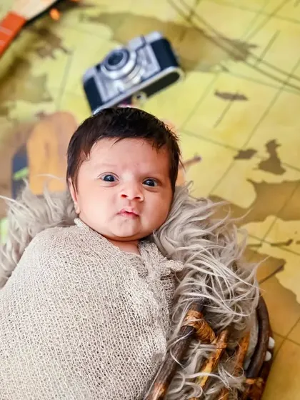A newborn wrapped in a swaddle lies on a world map, ready for life's big adventures.
