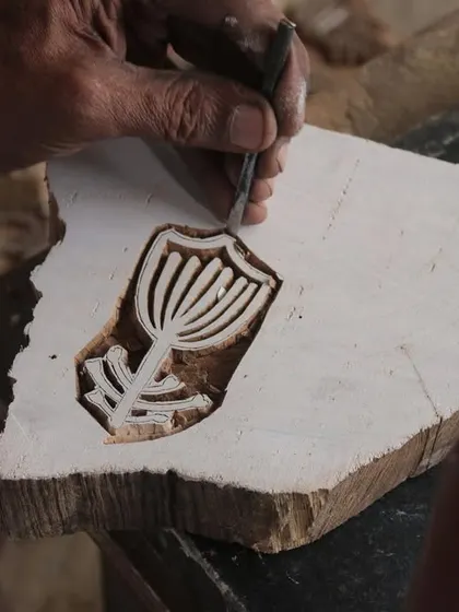 A close-up of a master carver's hands bringing a floral design to life on a teak block. This particular block was created for a collaborative workshop with the Fabric Workshop Museum in Philadelphia.