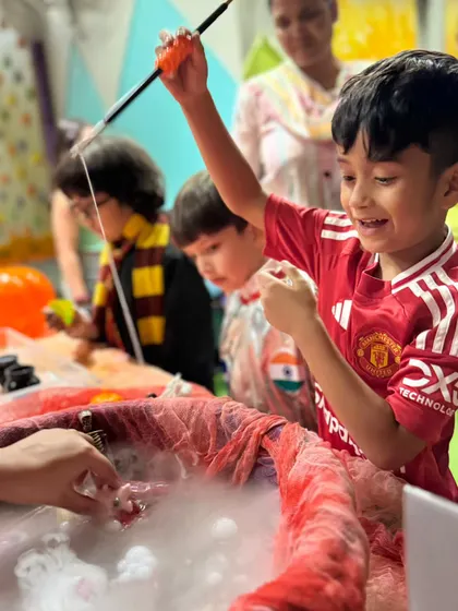 Success! This boy is thrilled as he 'fishes' for a spooky toy in a bubbling cauldron during our Halloween science activity.