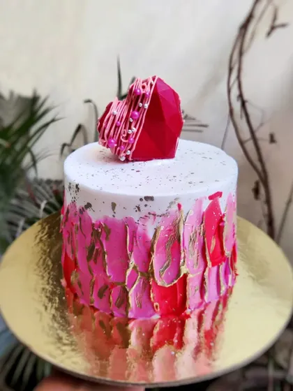 A cute heart for your sweetheart. This design features a textured pink and red buttercream effect with gold leaf and a geometric chocolate heart on top.