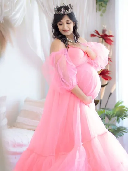 A dreamy and ethereal portrait in a soft pink off-the-shoulder gown. The natural light from the window adds a beautiful glow, making this a truly magical shot.