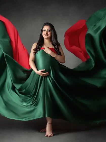 Another beautiful example of our flowing fabric photography. The vibrant red and green satin billows around the mom-to-be, creating a sense of movement and drama.
