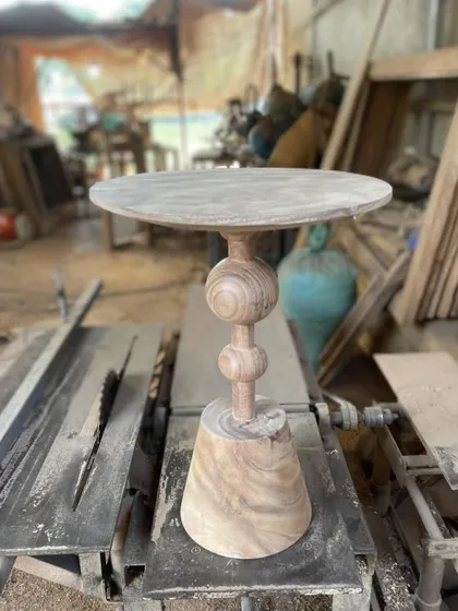 A turned-wood side table on a conical base, shown in the workshop.