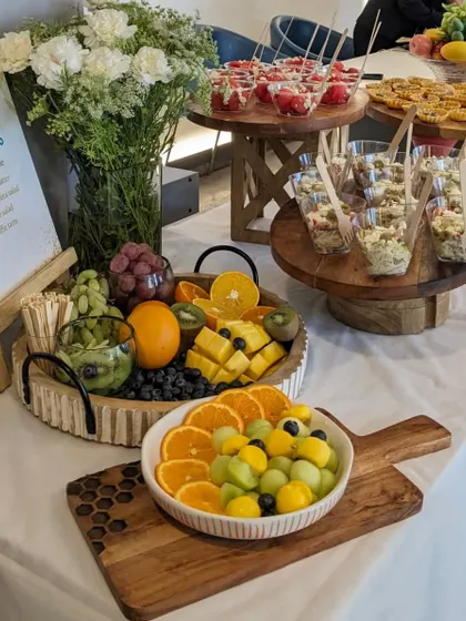 A healthy and refreshing grazing table designed for a wellness event. The focus is on fresh, vibrant fruits and light bites, including a colorful fruit platter, watermelon and feta salad cups, and Caesar salad cups.