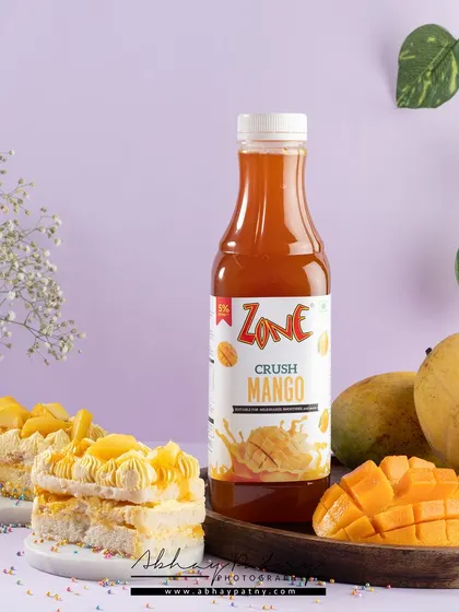A soft, pastel purple background complements the mango-colored drink, creating a gentle and appealing color palette. The fresh mango and pastry suggest a perfect dessert pairing.
