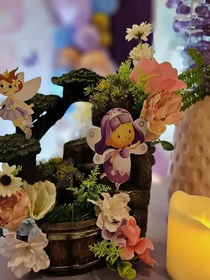 A close-up of a fairy-themed table centerpiece with a miniature waterfall and floral details.