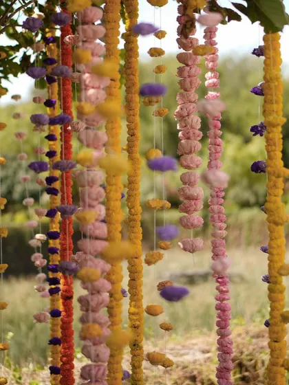A close-up of the hanging floral garlands from our Indian bazaar-themed event. The combination of marigolds and fluffy cotton-like accents creates a playful and unique textural element, turning a simple garland into a piece of art.